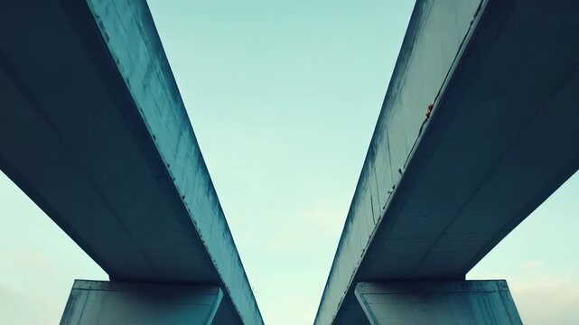 Concrete bridge beams converging into negative space, creating a v shape pattern from a low angle, highlighting architectural design, pathway, and modern infrastructure