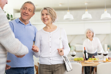 Obraz premium Two elderly couples warmly welcome each other as they gather for a festive holiday dinner in the home