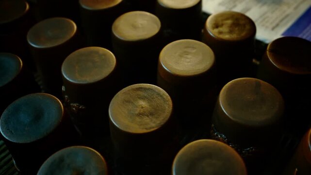 Top-down view of handmade clay cups placed upside down on a metal rack, featuring matte ceramic texture and minimalist cylindrical shapes.