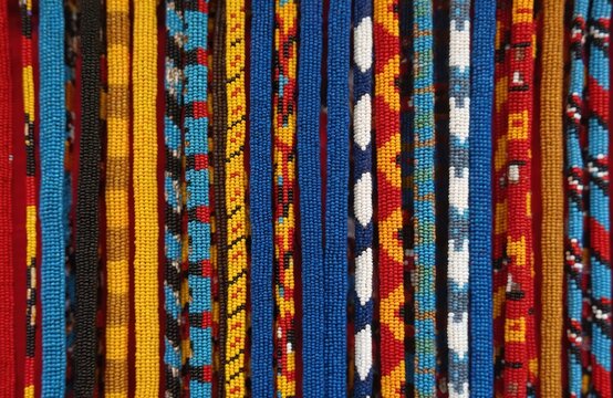 Colorful bead bracelets hang for sale. These handmade African Maasai accessories display vibrant patterns and traditional designs. Perfect for souvenirs or ethnic fashion.
