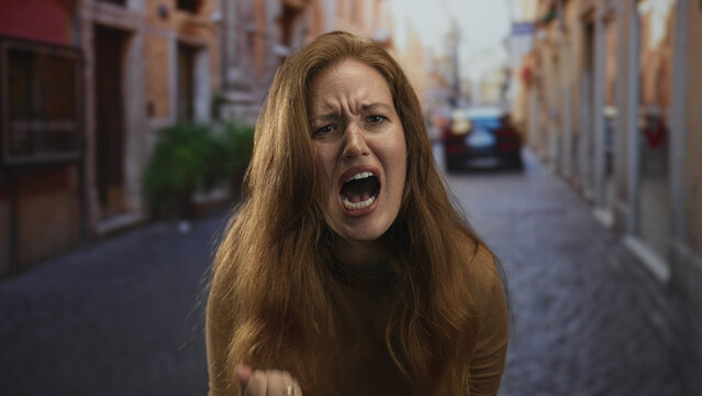 Woman with open mouth screaming amid sunlit vibrant narrow cobblestone city street scene; anger frustration.