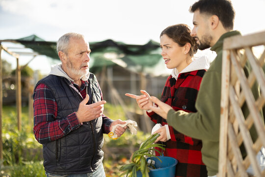 Married couple quarrels with mature male neighbor in suburban area garden. Ill-wishers, complaints and outrages from neighbors, shout outrages or claims