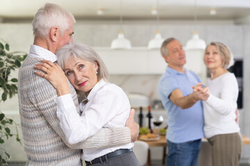 Obraz premium Couple dance at a house party in an apartment for elderly friends