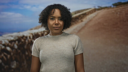 Woman turns head and stands in street with rocky canyon wall and cloudy sky overhead  contemplation. © Krakenimages.com
