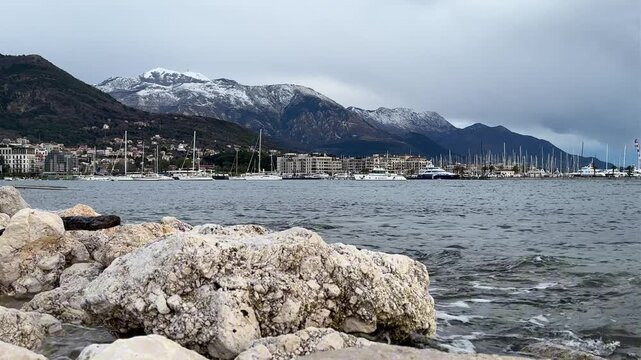 Fierce Ocean Waves Hit Jagged Rocky Coastlines. Chaotic Shoreline With Turbulent Waters And Distant Hill Ranges. Powerful Stormy Ocean Pounding Rugged Cliffs And Distant Mountainous Horizon