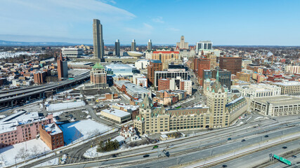 Obraz premium Aerial view of downtown Albany, New York in winter, featuring skyline, historic architecture, and snow-covered streets under clear sky.