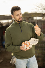 Man holding fresh eggs in a chicken coop © JackF