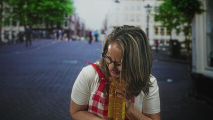 Fototapeta premium Woman cook holding a bottle of cooking oil with hands and smiling on street in apron and glasses; home cooking joy.