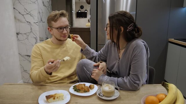 Cheerful pair enjoys cozy breakfast at home. Bright day starts with affectionate morning meal routine at residence. Happy couple shares cheerful and intimate breakfast experience to begin their day