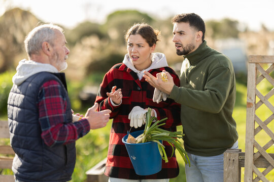 Married couple and an elderly man argue with each other while standing near fence on a small farm