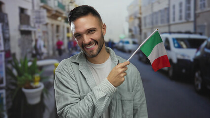 Young man smiling and holding italian flag in an urban street setting with cars and people visible...