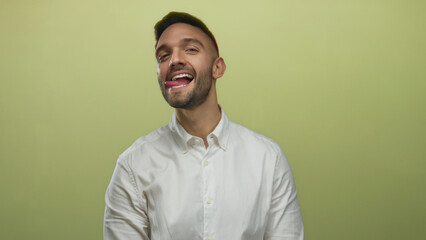 Obraz premium Young man playfully sticking his tongue out in front of a yellow background, expressing a cheerful mood.