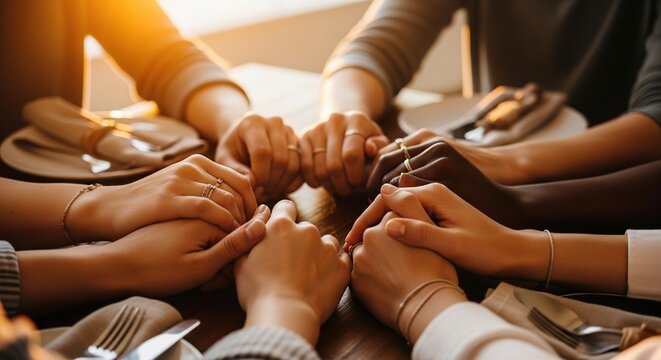 Diverse group of women holding hands around a table, representing unity, friendship, and shared support during a meal