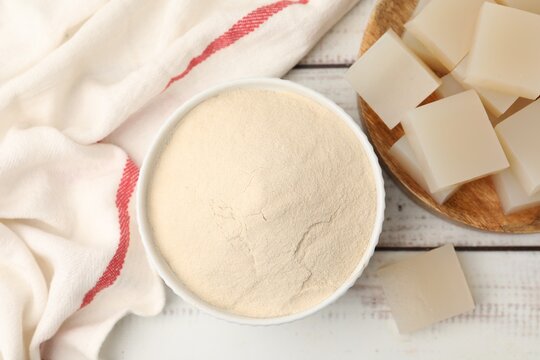 Homemade agar-agar jelly cubes and powder on white wooden table, flat lay