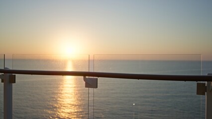 Obraz premium Glass balcony railing with defocused sunset over the ocean, soft bokeh outdoor; background backdrop copyspace template.