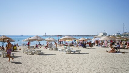 Obraz premium Sunny beach scene defocused and soft with umbrellas, loungers and shoreline in shallow blur outdoor; background backplate copyspace calm.