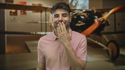 Man finger to lips in museum hall next to large vintage airplane propeller display with warm ambient lighting  silence hush. © Krakenimages.com