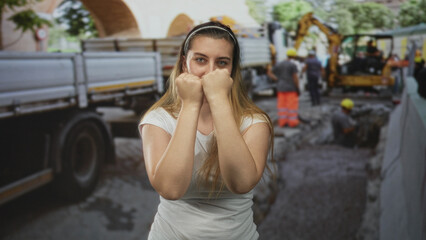 Fototapeta premium Woman with fists raised in guard on street construction site wearing white tshirt and headband; determination resilience.