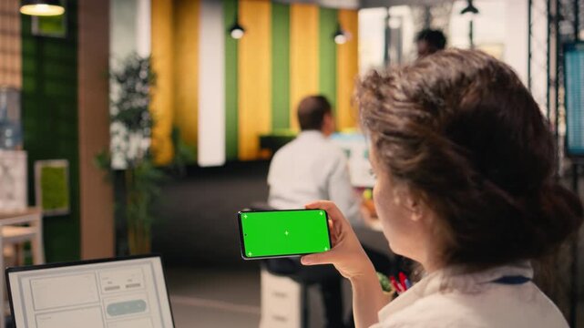 Chroma key on smartphone held by woman worker in corporate environment, reviewing business intel and visual data, analytics and performance metrics used for task management. Forecasting reports.