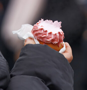 Traditional Czech sponge dessert Indian called Indian with pink icing held in hand at Naplavka riverside market in Prague, popular urban lifestyle hot spot.