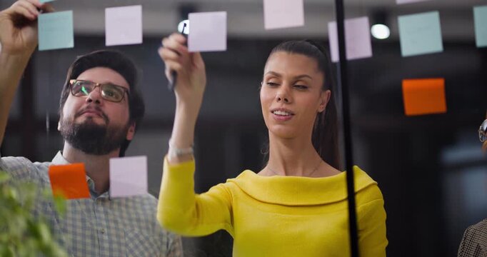 Team works together in office to organize ideas on sticky notes at the meeting table during afternoon brainstorming session