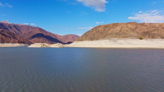 Aerial view captures tranquil artificial lake Orto Tokoy bordered by arid mountains in Kyrgyzstan. Captured in autumn 2025.