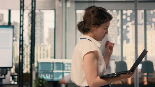 Agitated woman pacing the floor in modern office and being impatient, fidgeting and walking back and forth due to nervousness. Focused and anxious female worker, business intelligence.