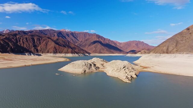 Aerial view captures vast mountainous region with calm artificial lake Orto Tokoy and islands in Kyrgyzstan at autumn 2025. Dolly forward camera movement.