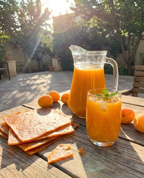 Refreshing pitcher and glass of Qamar Al-Din apricot juice with dried apricot sheets in sunlight