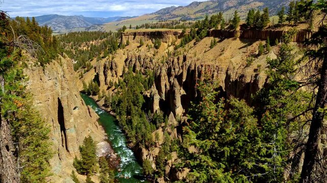 amazing view Yellowstone National park Wyoming USA green emerald color water river canyon and red cliff with pine trees on a cloudy day