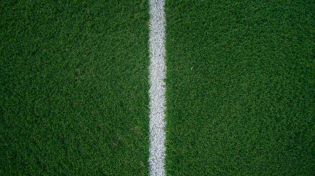 Top down view of a soccer field featuring a detailed grass texture and a bold white sideline. The image showcases close up green turf with visible blades.