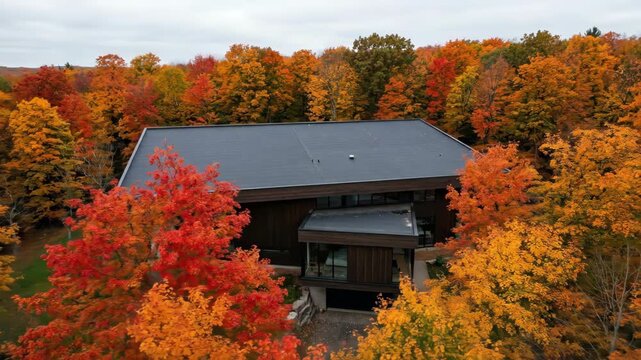 Aerial View of Modern House in Dense Autumn Forest with Vibrant Foliage