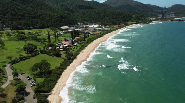 Aerial view of a sandy beach with green hills and ocean waves in Itapema, Brazil