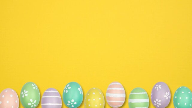 Colorful Easter Egg bottom border on a yellow background. Up down, stop motion. Copy space.