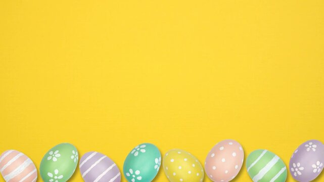 Colorful dancing Easter Egg bottom border on a yellow background. Stop motion. Copy space.