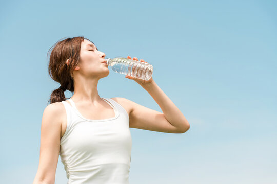 A woman drinking water while exercising (heatstroke prevention, hydration, mineral water)