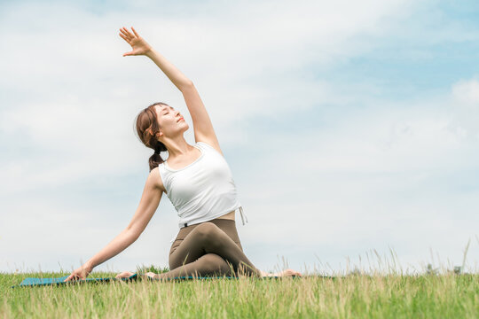 A woman doing yoga, stretching, Pilates, and body care in the grassland (healthcare, diet, maintaining health)
