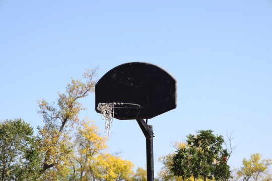 neglected string basketball net in need of repair against clear blue autumn sky