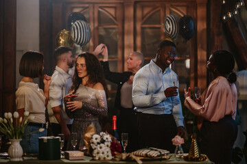 Diverse friends enjoying a celebration, toasting with champagne, socializing and networking at an indoor party