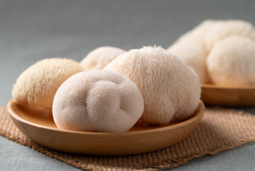 Fresh Lion's Mane mushroom (Hericium erinaceus) on wooden plate, known for nootropic benefits and medicinal properties © nungning20