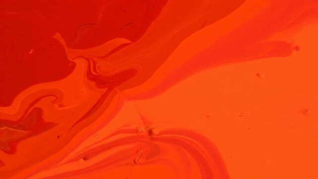 Abstract Orange Paint Swirls - This video features a close-up shot of swirling, glossy orange paint. The paint consists of multiple hues of orange that blend together to create a striking abstract