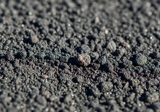 Closeup of dark granular material likely volcanic ash or slag with sparkling highlights