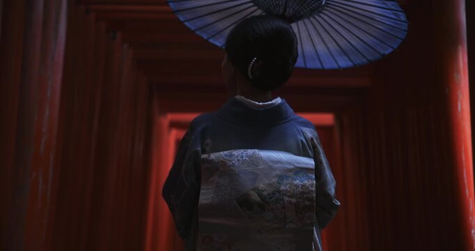 Cinematic silhouette of mysterious Japanese woman in kimono standing in shadows of torii gates