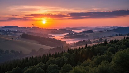 Fototapeta premium Golden Sunset Over Rolling Hills: A breathtaking landscape unfolds as the sun dips below the horizon, painting the sky with fiery hues and casting a warm glow over undulating hills and lush forests.