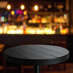 A round, dark table in focus against a blurred bar background