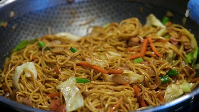 Pancit preparation in a kitchen in the Philippines with fresh vegetables and noodles.