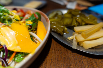 Fresh salad with mango and pickled vegetables served on wooden table