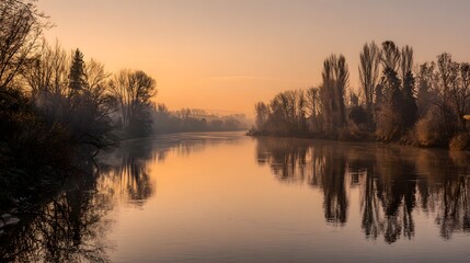 Obraz premium Serene River Landscape at Sunset with Reflecting Trees and Golden Sky.