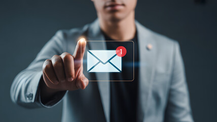 Businessman in gray suit interacting with virtual email notification icon with unread message count displayed on transparent screen