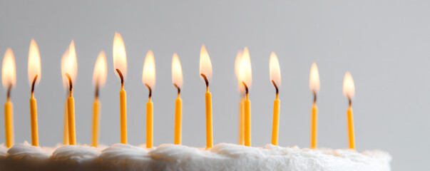 Low-angle close-up of candle flames against white backdrop, cake minimally visible 32k